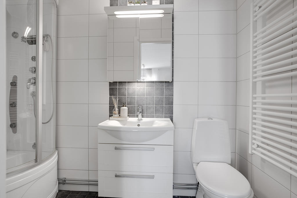 Fint renoverat badrum med duschkabin, kommod och spegelskåp