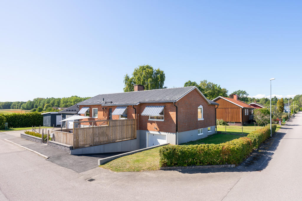 Asfalterad uppfart till garage i huskroppen med brunnfåra vid infart. 