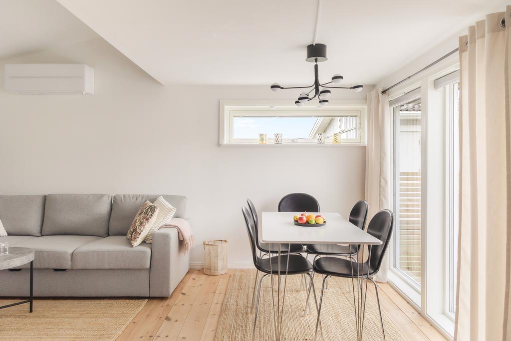 Öppen och social planlösning med plats för både soffgrupp och matbord. De ljusa ytskikten tillsammans med trägolvet skapar ett harmoniskt intryck.
