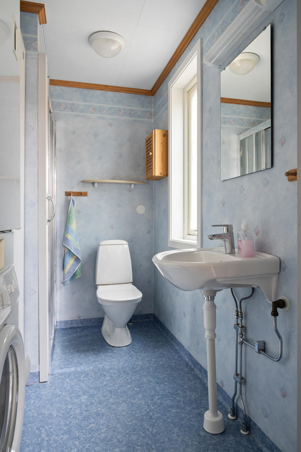 Det första badrummet är funktionellt med dusch, wc, handfat och spegel. Ett praktiskt torkskåp kompletterar inredningen och erbjuder smart förvaring.