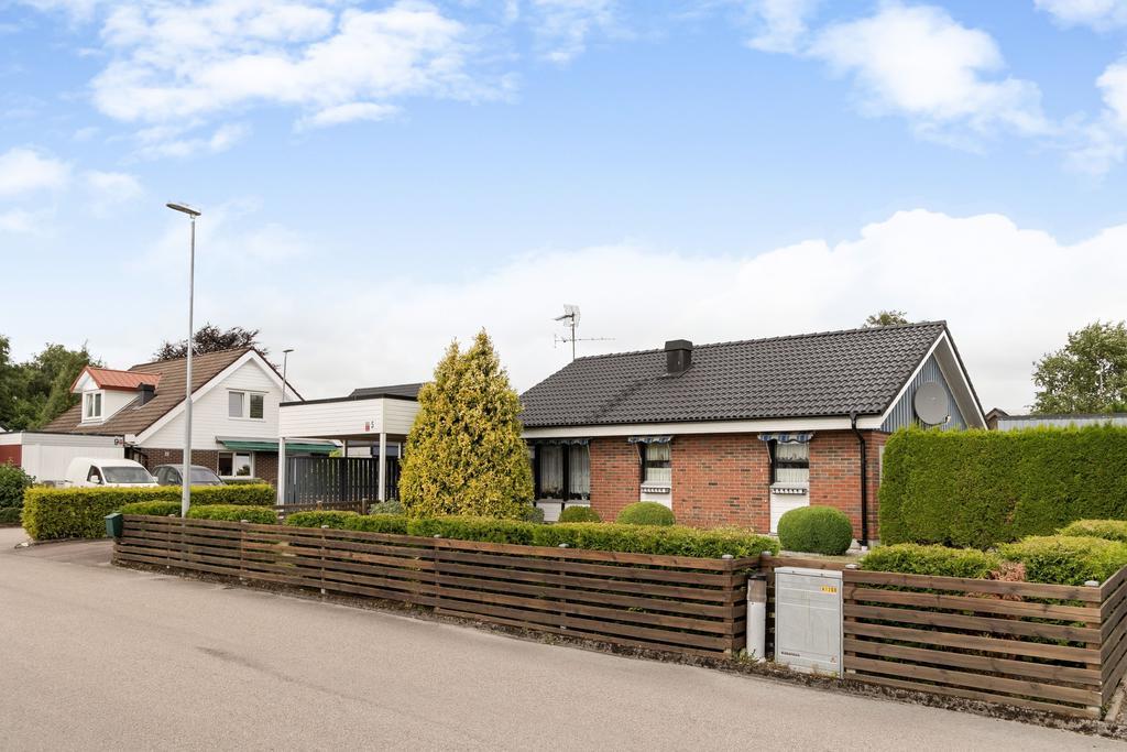 Bostadens framsida med grönskande omgivningar och en välkomnande entré.