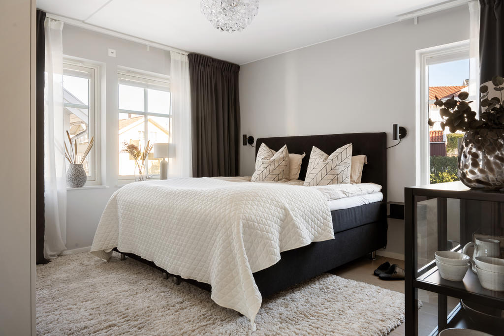 Rofyllt och smakfullt sovrum med en harmonisk färgsättning som skapar en elegant hotellkänsla. De ljusa ytskikten, den vackra parketten och det naturliga ljusinsläppet bidrar till en avkopplande atmosfär. Här finns gott om plats för dubbelsäng med tillhörande möblemang samt garderober som erbjuder praktisk och stilren förvaring.