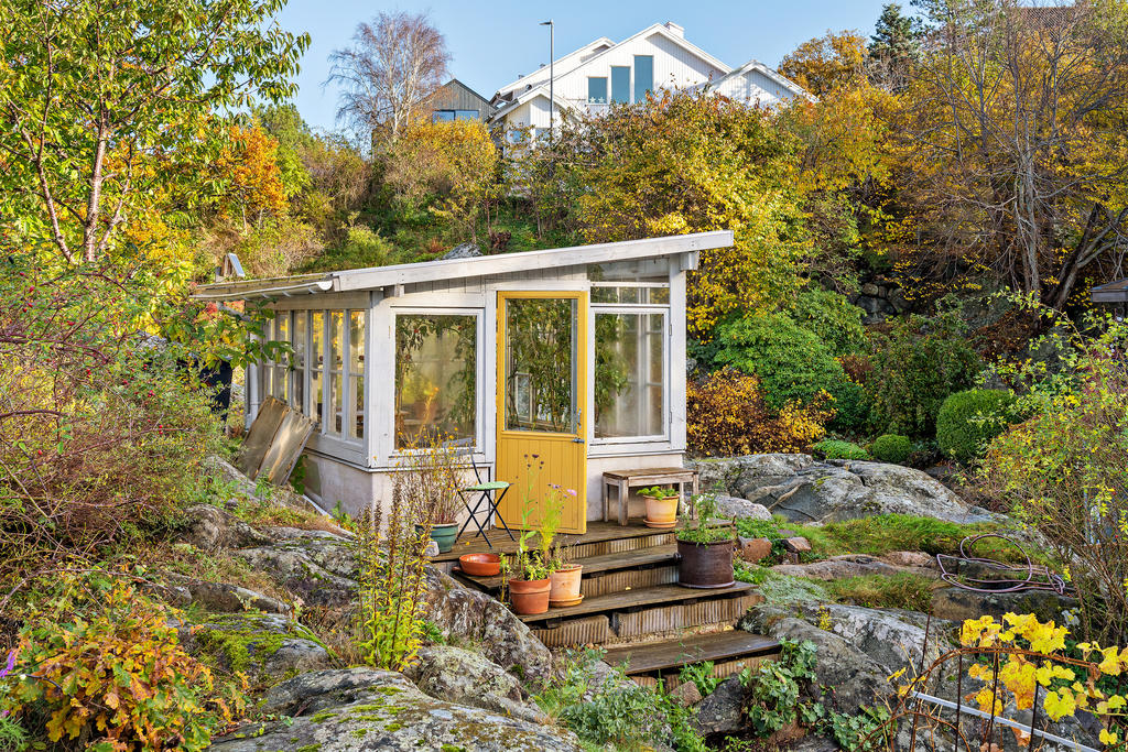 Det charmiga växthuset är byggt av återbrukade gamla fönster och ligger vackert inbäddat bland grönska och naturliga bergspartier. En alldeles egen liten oas för odling och avkoppling.