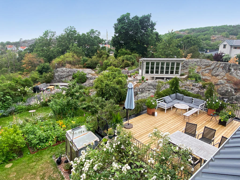 Här ser man verkligen hur trädgården kommer till sin rätt under sommaren, med blomstrande rabatter, grönsaksodlingar och vackra buskar. Den stora terrassen rymmer både matgrupp och loungemöbler, med fin utsikt över den omsorgsfullt anlagda trädgården.